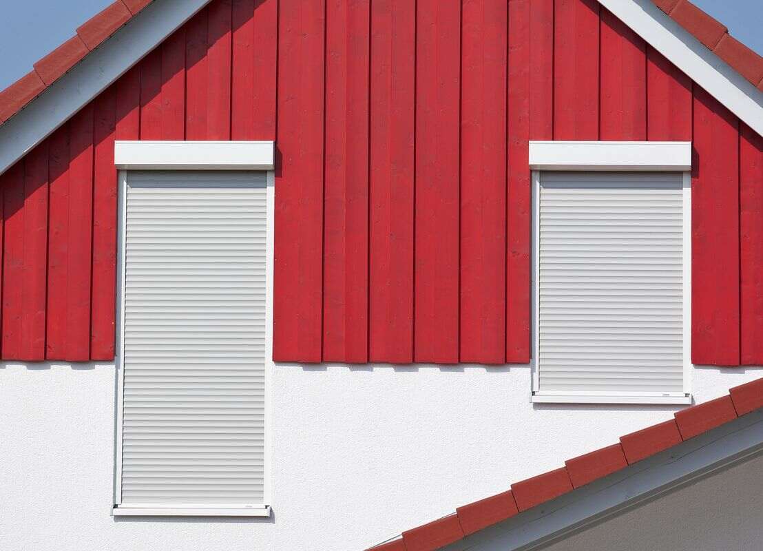 Volets roulants blancs sur façade rouge